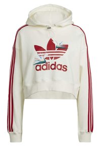 Krátká krémová mikina s kapucí s červeným vzorem tří pruhů na rukávech, s červeným logem Adidas a vyšívanými detaily ptáků v modré a bílé barvě.