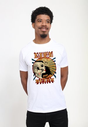 Camiseta blanca con un gráfico de una cara de calavera con tatuajes intrincados y el texto “LA VIDA sobre la MUERTE” en rojo, rodeado de rayos de sol.