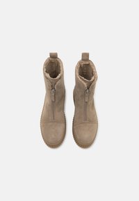 Μπεζ σουέτ μποτάκια μέχρι τον αστράγαλο με χνουδωτή επένδυση, διαθέτουν μπροστινό φερμουάρ, λουράκι στο πίσω μέρος και υφή από καουτσούκ στη σόλα.