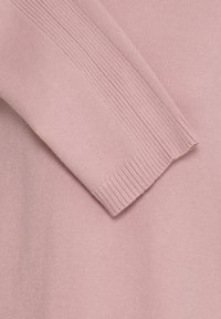 Tissu tricoté rose doux avec une manche longue dotée de poignets côtelés et d’un subtil côtelé vertical le long du bras.