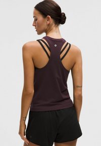 Bordeaux tanktop met zwarte bandjes, met een racerback ontwerp en gestructureerde stof. Gemaakt met zwarte shorts, zichtbaar een tattoo op de arm.