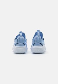 Un paio di scarpe da ginnastica azzurro chiaro viste da dietro, con suole bianche e linguette sul tallone.