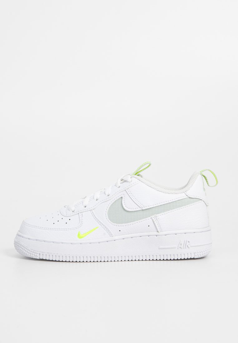 Les baskets Nike Air Force 1 blanches présentent un dessus en cuir lisse, des accents à motif en grille verte et un logo jaune fluo. Semelle en caoutchouc texturé.