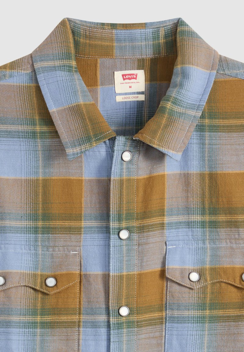 Geruit overhemd met knopen, met blauwe, mosterdgele en groene vierkanten, voorzien van metalen drukknopen en twee borstzakken met kleppen.