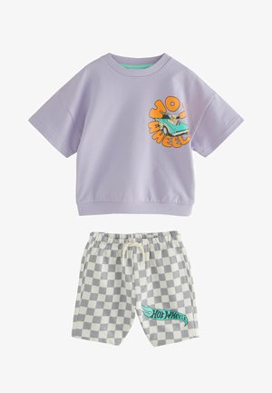 Camicia lilla a maniche corte con grafica di un'auto stampata e testo arancione, abbinata a pantaloncini a quadri con logo "Hot Wheels" turchese.