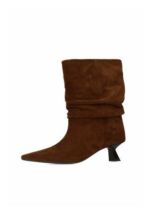 Bruine suède laarzen tot halverwege de kuit met een slappe schacht, puntige neus en een korte, uitlopende zwarte hak.