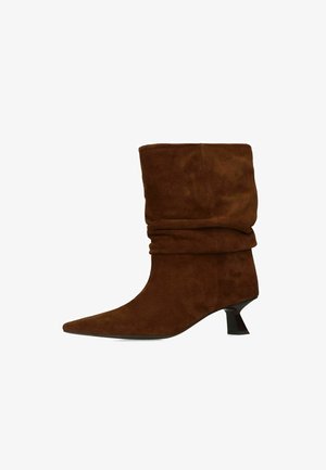 Bruine suède laarzen tot halverwege de kuit met een slappe schacht, puntige neus en een korte, uitlopende zwarte hak.
