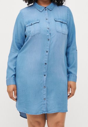 Jasnoniebieska sukienka koszulowa z denimu z przodem na guziki, kołnierzykiem, dwoma kieszeniami na piersi i długimi rękawami. Zaokrąglony dół z tyłu.