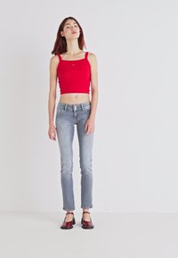 Top cropped vermelho, jeans slim-fit azul claro e sapatilhas bordô. Design simples com uma textura suave e uma silhueta ajustada.