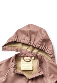 Giacca impermeabile rosa con interno beige, dotata di cappuccio, chiusura con zip e bottoni a pressione. Include un'etichetta di cura visibile all'interno.