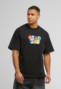 Camiseta de algodón negra con un diseño gráfico colorido de formas circulares y el texto "HOME BOY" en el centro. Corte relajado, mangas cortas.