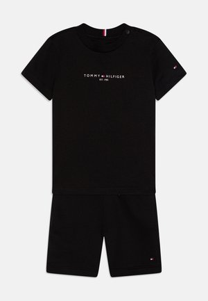 Svart bomull T-skjorte og shorts-sett med rund hals og korte ermer. Frontlogo i hvitt. Knappe-detall ved skulderen.