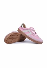 Paire de baskets basses roses avec côtés blancs, lacets roses, semelles en caoutchouc marron et détail métallique doré sur le talon, sur fond blanc.