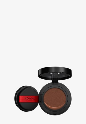 Kompaktowy podkład L'Oréal Paris w okrągłym czarnym etui, z czerwonym paskiem i miękkim brązowym pudrem w środku. Kompakt otwiera się na zawiasie.