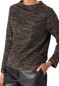 Pull marron texturé avec un col bateau et des manches longues, fabriqué à partir d'un fil multicolore. Associé à un pantalon en cuir noir lisse.