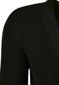 Svart ribbestrikket cardigan med dyp V-hals. Stoffet er teksturert, med vertikale linjer og en tettsittende passform.