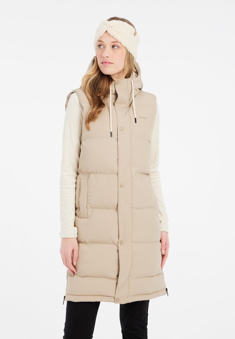 Gilet matelassé beige avec capuche, fermetures à pression à l'avant, poches latérales et un bandeau texturé crème. Matériau doux, design jusqu'aux genoux.