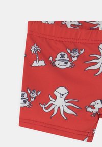 Calções de banho vermelhos com desenhos de polvos de cartoons, caranguejos e palmeiras. Feitos de um tecido suave com um confortável cós elástico.