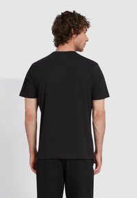 T-shirt nera a maniche corte con una vestibilità rilassata, scollatura rotonda e una texture liscia e morbida. Nessun motivo o logo visibile.