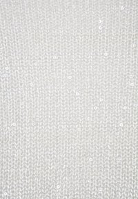 Biała dzianina o teksturowanej powierzchni, ozdobiona małymi, błyszczącymi cekinami, które dodają subtelnego dekoracyjnego akcentu.