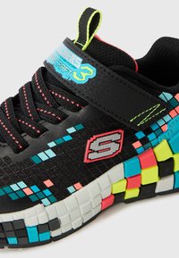 Mustade spordijalatsid, millel on tekstuuriga pealmine osa, kus on värviline pikslimuster sinises, roosas ja kollases. Üksikasjadena on ka Velcro riba ja logo.