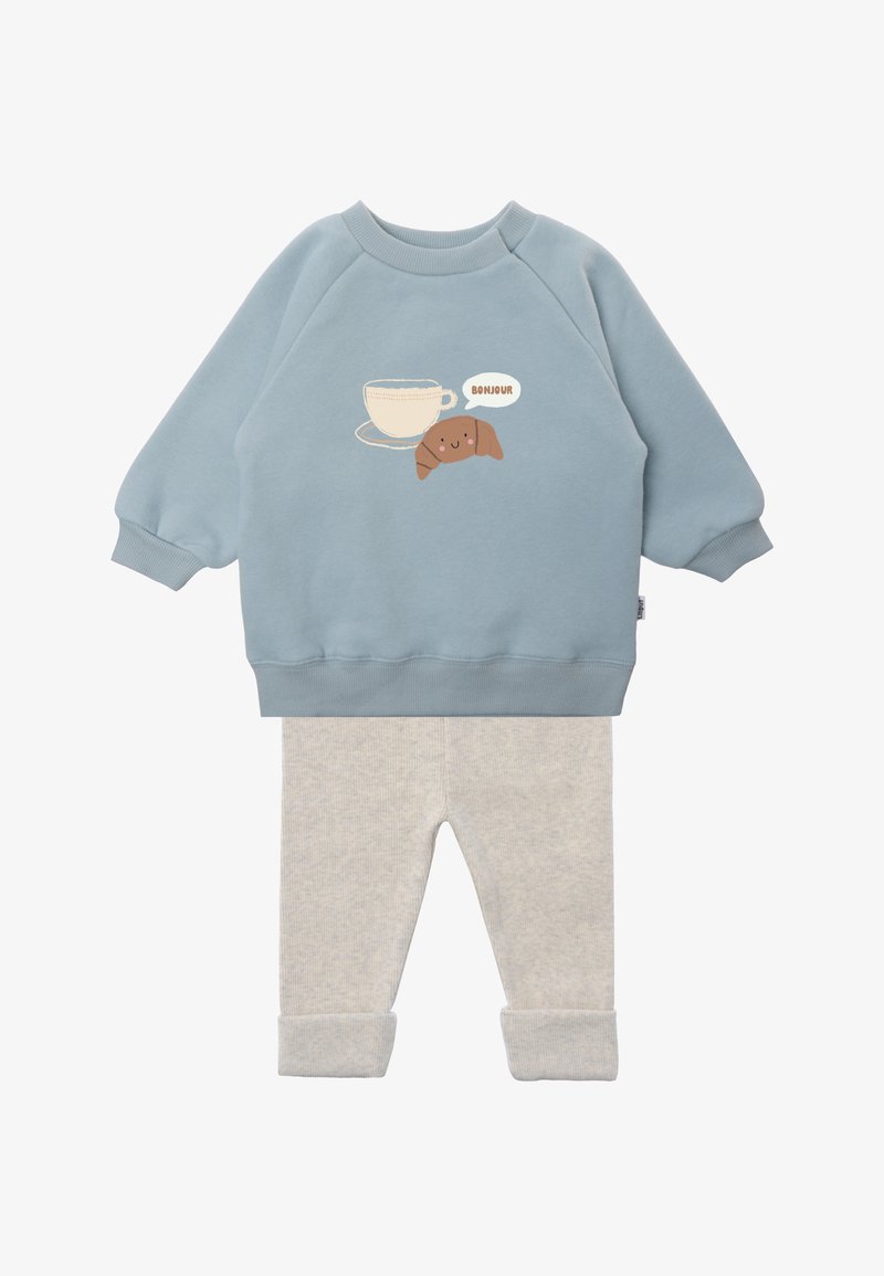 Light blue long-sleeve top with cup and smiling croissant saying "Bonjour," paired with light beige ribbed pants with cuffs.