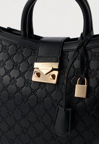 Crna torbica od umjetne kože s ugraviranim cvjetnim uzorkom, zlatnim hardverom, detaljem u obliku brave i dvostrukim ručkama. Ima strukturirani dizajn.