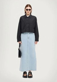 Svart, cropped knappjakke, lys blå maxi denimskjørt, overdimensjonert svart håndveske, svarte chunky sandaler og mørke solbriller.