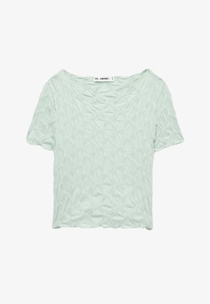 Blouse vert clair à manches courtes avec motif géométrique texturé et encolure ronde, posée à plat sur fond blanc.