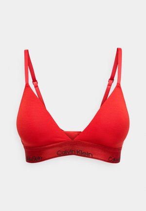 Sarkans kokvilnas trijstūra krūšturis ar regulējamām sarkanām siksnām un mīkstu elastīgu jostu ar melnu "Calvin Klein" logo.