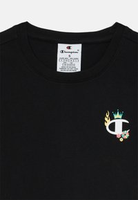 Μαύρο βαμβακερό T-shirt με εκτυπωμένο λογότυπο που απεικονίζει φλόγες, στέμμα και λουλούδια. Σχέδιο με στρογγυλή λαιμόκοψη και ετικέτα στο εσωτερικό του λαιμού. Μέγεθος S.