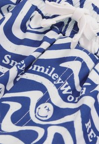 Kék és fehér mintás fürdőnadrágok hullámos mintákkal, mosolygós arcokkal és zsinóros zárással, texturált anyagból.
