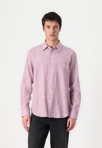Light pink button-up shirt with thin vertical stripes in darker shades. Features a chest pocket and relaxed fit. Fabric appears textured.