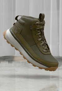 Olive roheline kõrgema säärega sneaker, millel on tekstuuriga ülemine osa, pehmendatud krae, peegeldavad detailid ja sügava mustriga kummitald. Omab vastupidavaid paelu ja logo.