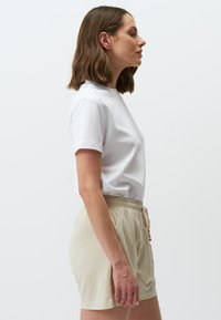 Witte katoenen t-shirt met een ronde hals, gecombineerd met lichtbeige shorts met een elastische tailleband en zijzakken.