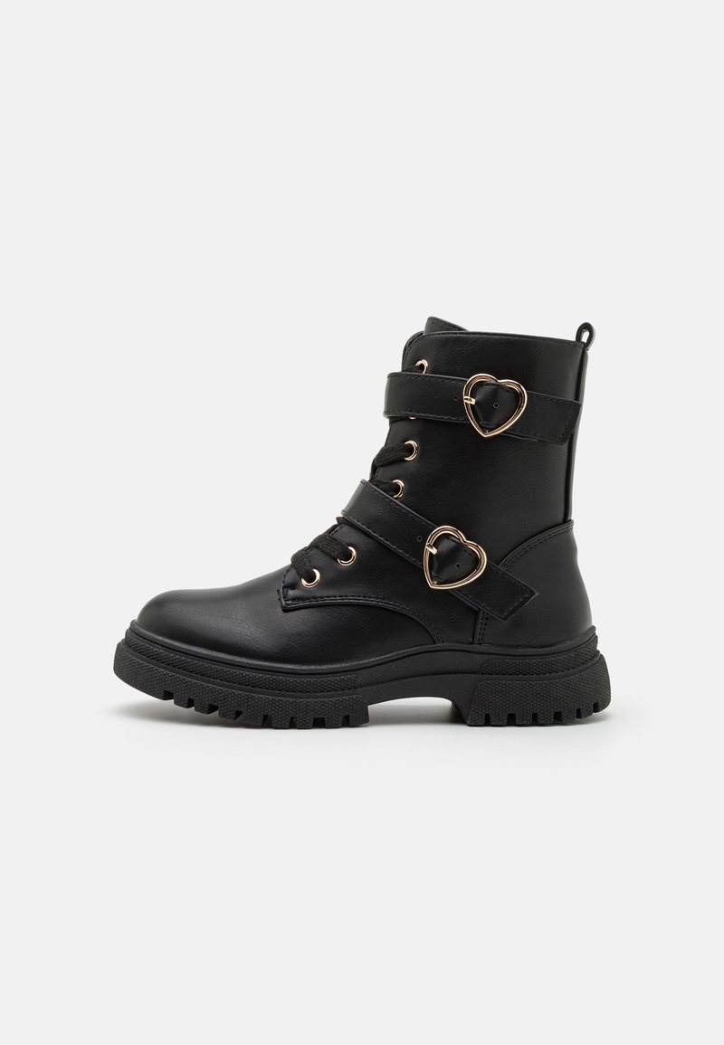 Bottines noires en matériau synthétique, ornées d'accents en forme de cœur doré, de sangles à clous et d'une semelle en caoutchouc texturé.