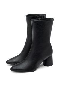 Par de botas negras de media caña con cuero texturizado, punteras afiladas, cremalleras laterales y tacones cuadrados gruesos sobre un fondo blanco.