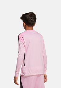 Jersey sportivo a maniche lunghe in rosa chiaro con lati neri, realizzato in tessuto morbido e traspirante, con collo tondo e vestibilità atletica.
