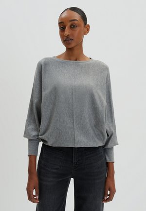 Pullover grigio leggero con scollatura a barca, vestibilità morbida e maniche lunghe. Indossato con jeans neri, che mette in evidenza un look rilassato e casual.