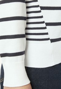 Gestrickter Pullover mit horizontalen navy Streifen auf weißem Hintergrund, mit gerippten Bündchen und Saum sowie einer leicht lockeren Passform.