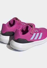 Zapatillas deportivas rosas con una parte superior de malla texturizada, acentos en blanco, una correa de gancho y bucle, y una suela blanca duradera con detalles en negro.