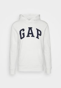 Felpa bianca con cappuccio, dotata di tasca a marsupio frontale, cordino e grande logo "GAP" in colore navy sul petto, in un font audace.