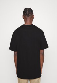 Black short-sleeve t-shirt, made of cotton. Features a crew neck and a relaxed fit. Back view shows no graphics or patterns.