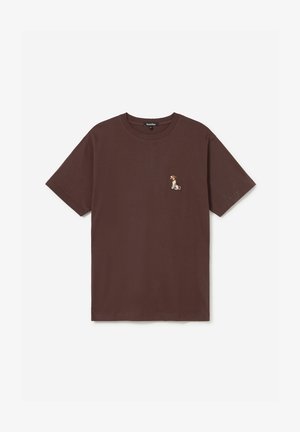 T-shirt marron à manches courtes avec un petit chien assis brodé sur le côté gauche de la poitrine et un col rond.