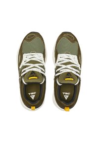 Chaussures de sport vert olive en mesh et daim, lacets blancs, logo sur la languette et accent jaune au talon.