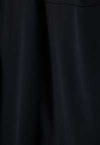 Un tissu noir présentant une surface lisse et texturée avec un léger éclat ; il possède des bords et des coutures nets, adapté à divers designs de vêtements.