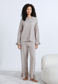 Σετ πιτζάμες καρώ σε καφέ και λευκό με βολάν στα μανίκια, πουκάμισο με κουμπιά και παντελόνι που ταιριάζει, με λεπτή υφή.