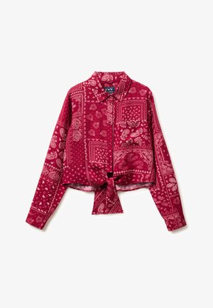 Chemise rouge à manches longues avec boutons, imprimée de motifs bandana cachemire blancs, avec un détail noué à l'avant, posée à plat sur un fond blanc.