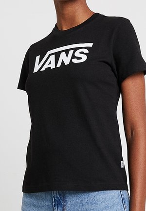 Sort t-shirt med korte ærmer og hvid Vans-logo på brystet, båret med lyseblå jeans.