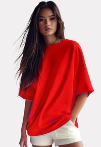 Rode oversized t-shirt met korte mouwen, een gladde textuur en een losse pasvorm. Draag het met witte shorts, tegen een neutrale achtergrond.